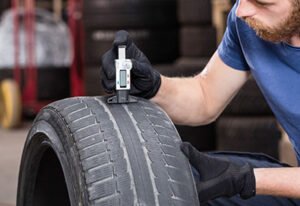 Conductor revisando presión de neumáticos antes viaje